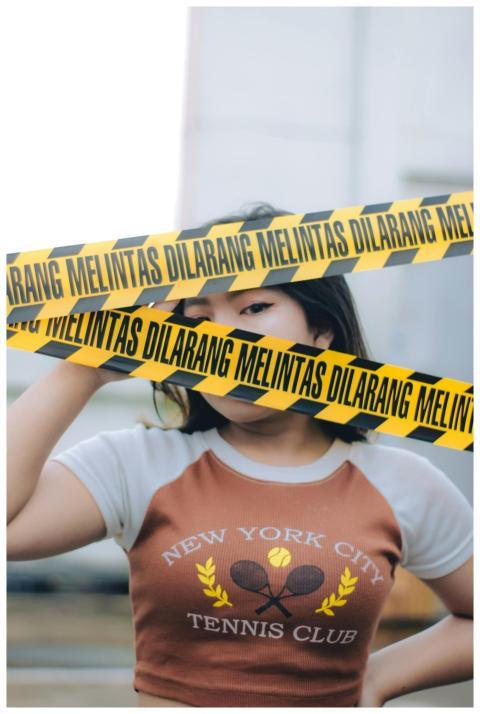 A stylish woman poses behind yellow caution tape i