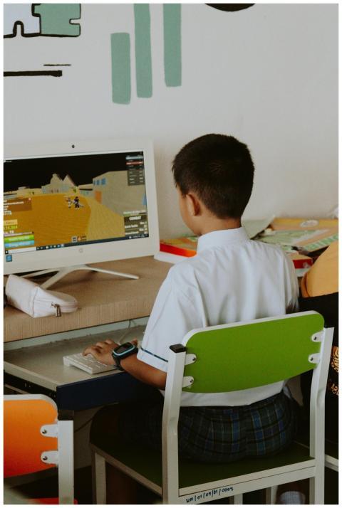 Young boy in school uniform playing computer games