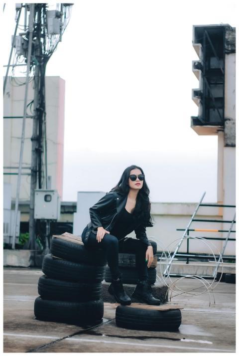A fashionable woman in black sitting on tires outd
