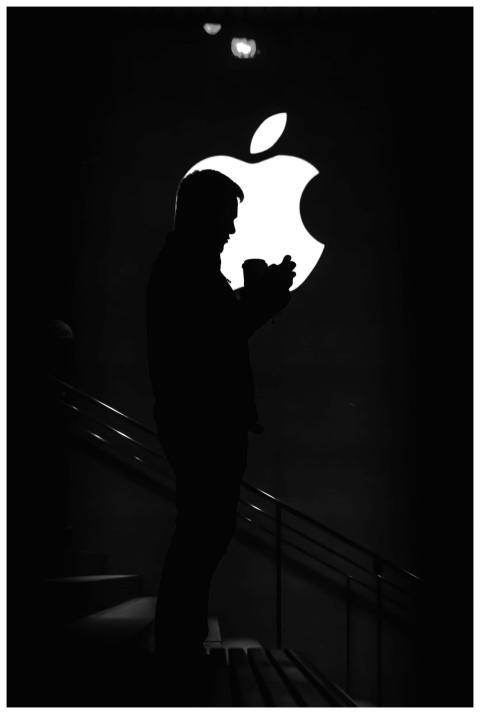 Silhouetted man against bright Apple logo, creatin