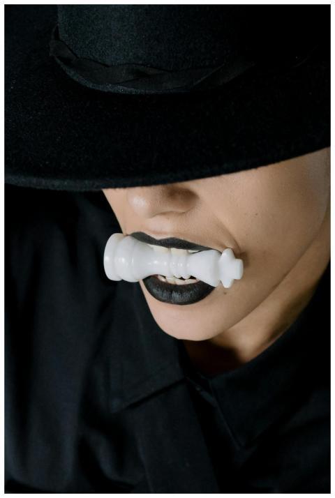 Close-up of a mysterious person biting a white che