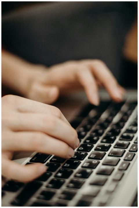 Close-up shot of hands typing on a laptop keyboard