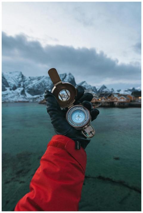A gloved hand holds a compass in Reine, Lofoten Is