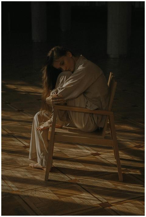 A woman in casual attire sits alone on a chair in