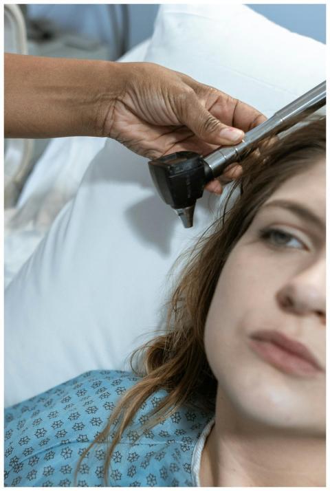 A nurse uses an ear thermometer to check the tempe