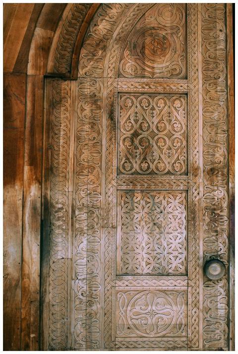 Exterior of aged shabby wooden door with carved or