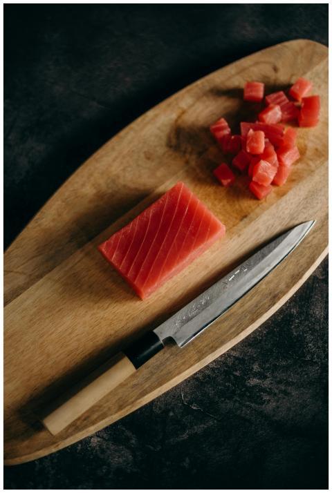 Close-up of fresh tuna cubes and knife on a wooden