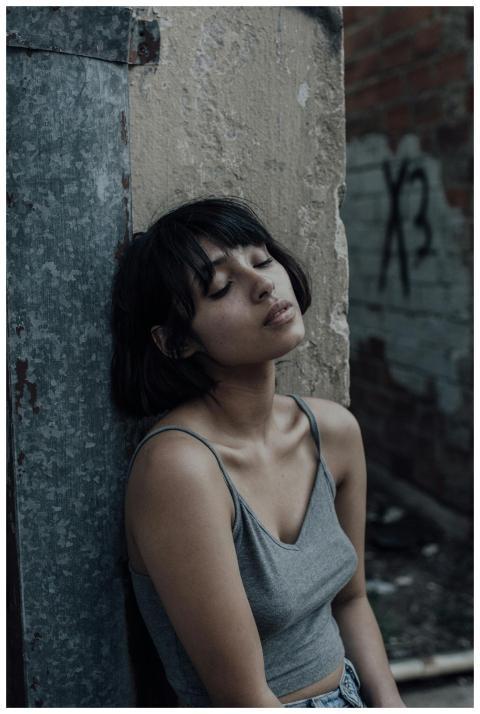 A young woman sits with eyes closed in a quiet urb