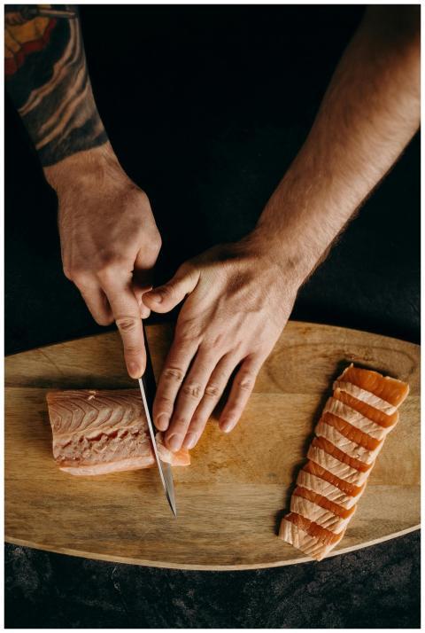 Expert chef slicing fresh salmon on a wooden board