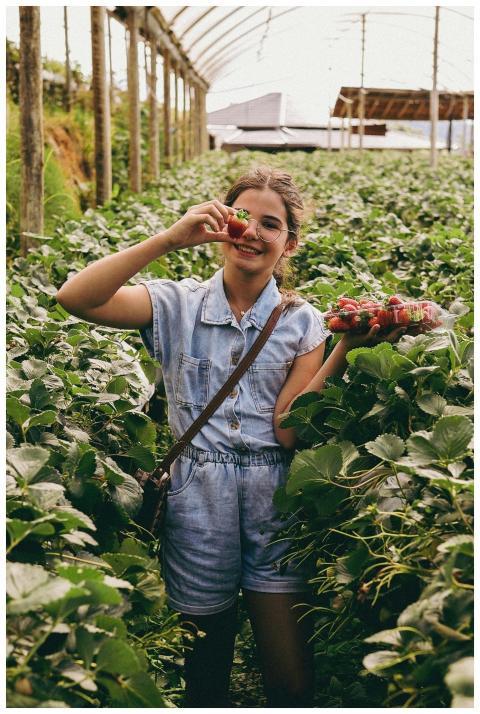 Young girl in a greenhouse smiling and holding fre