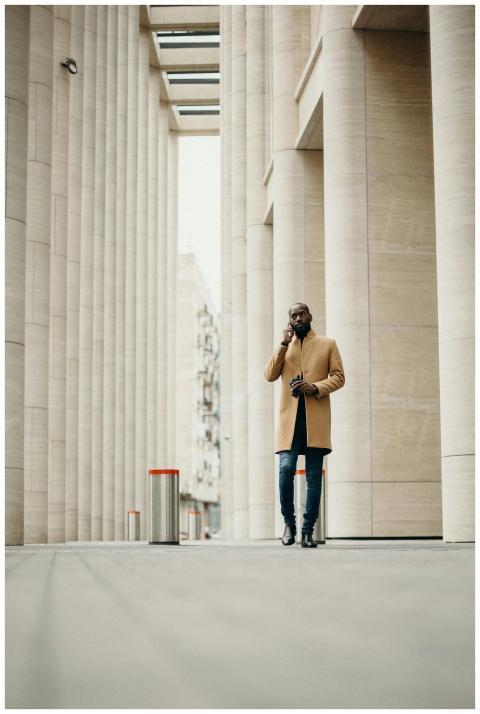 A fashionable man in a coat talking on the phone,