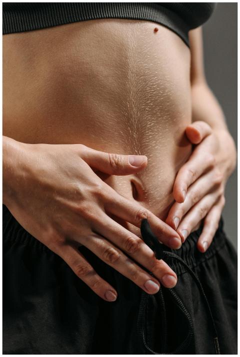 Hands resting on a toned stomach in sportswear, re