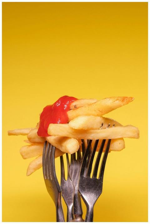 Yummy french fries with ketchup on forks near yell