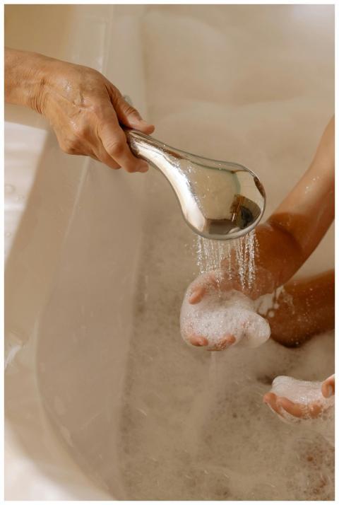 Close-up of hands washing with a shower head in a
