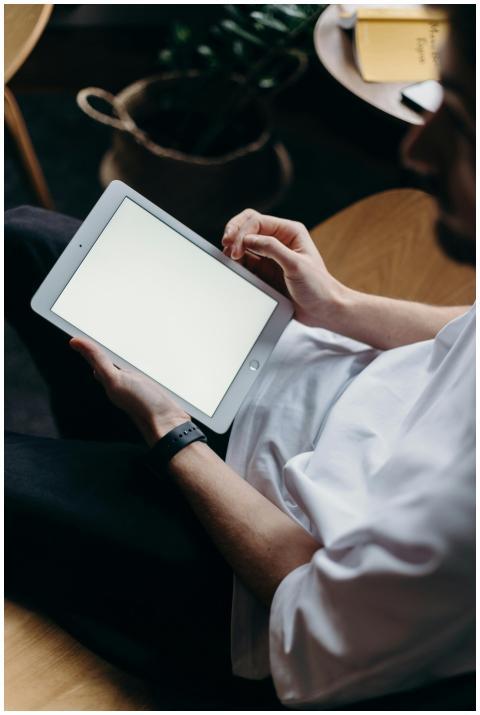 Adult male in casual attire holding a tablet with