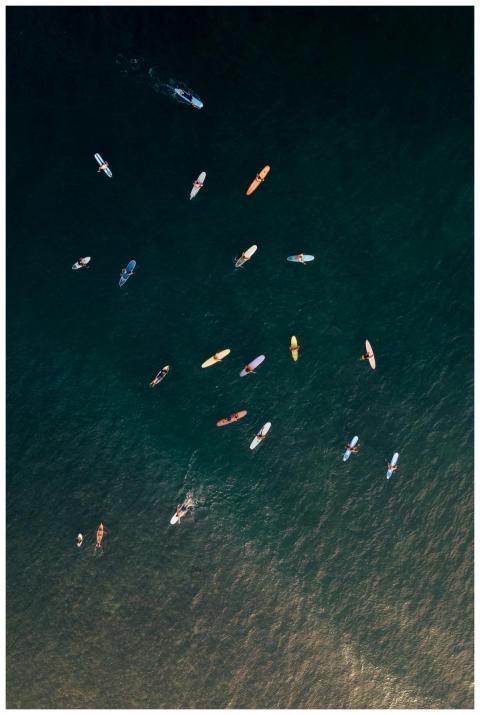 Top-down aerial view of surfers with colorful boar