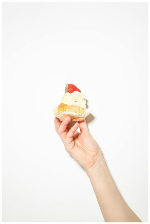Close-up of a hand holding a strawberry topped cre