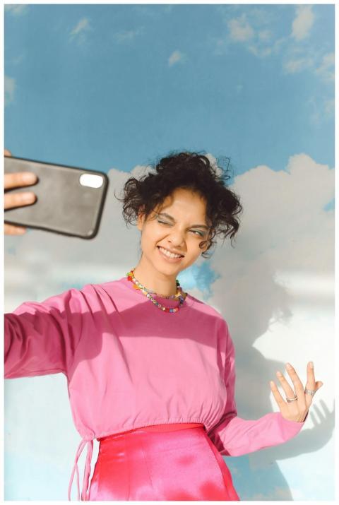 Smiling teenage girl in pink sweater taking a self