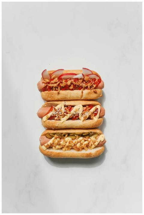 Three gourmet hot dogs with various toppings on a