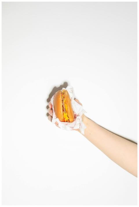 Close-up of a hand holding a cheeseburger wrapped