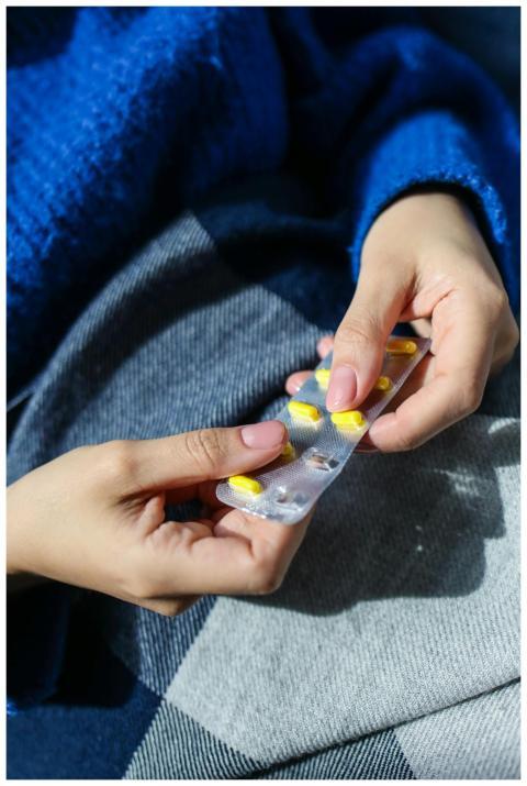 Close-up of hands holding a blister pack of yellow