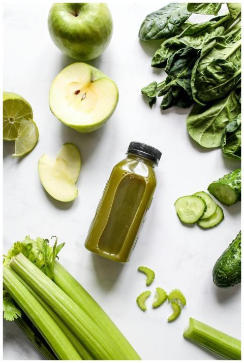 Flatlay of fresh green juice with vegetables and f