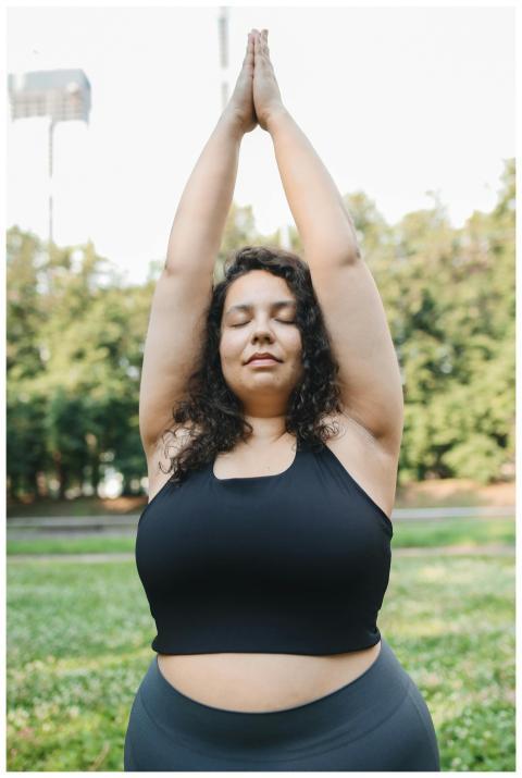 Plus size woman practicing yoga in a serene park s