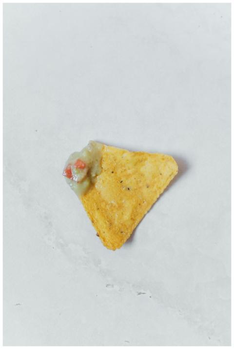 A close-up of a tortilla chip with guacamole dip o