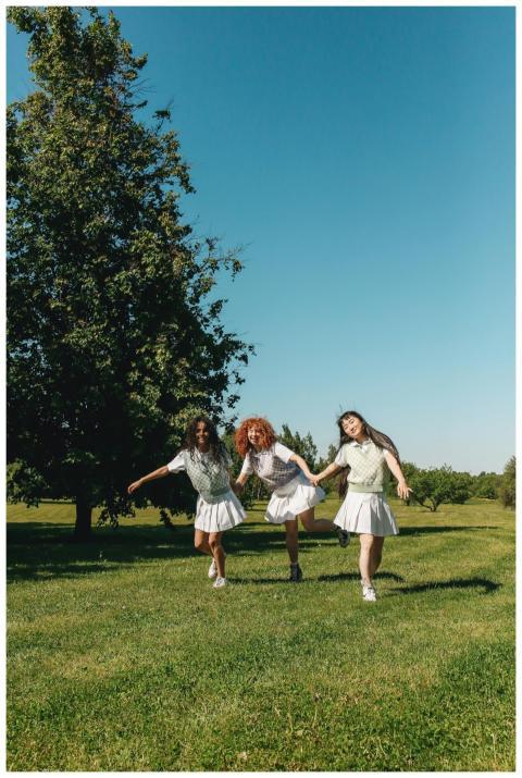 Three young women running joyfully on a sunny day