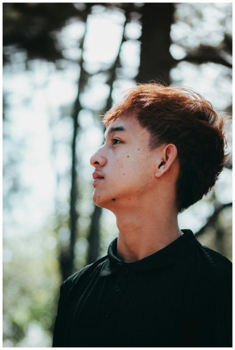 Profile shot of a young man outdoors with blurred