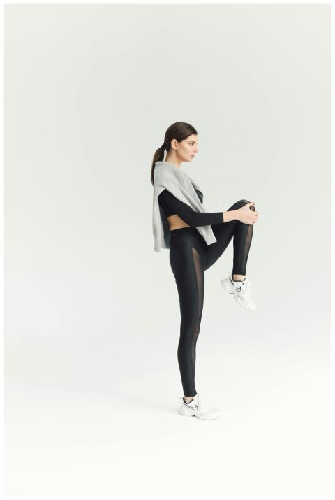 Woman in modern sportswear stretching indoors, sho
