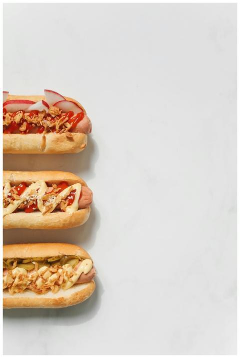 Three gourmet hot dogs topped with various ingredi