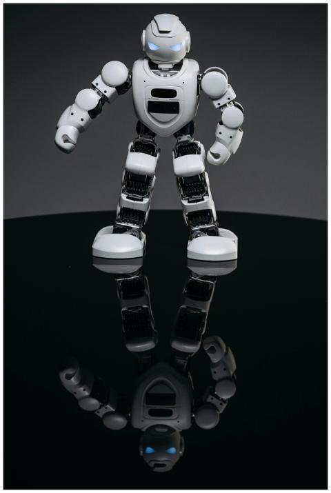 A small, futuristic robot toy stands on a reflecti