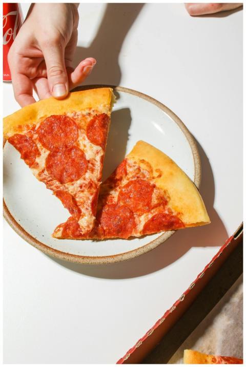 Close-up of pepperoni pizza slice being picked up