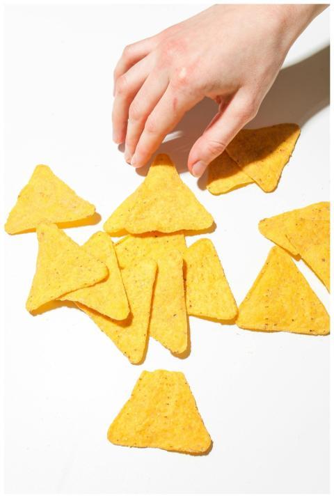 Close-up of a hand reaching for triangular nacho c