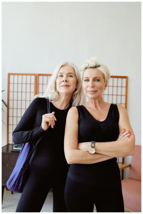 Two senior women in stylish activewear pose confid