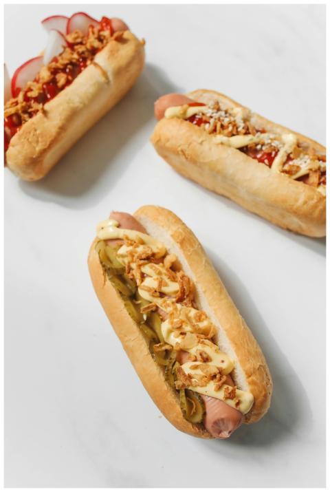 Three gourmet hot dogs with various toppings on a