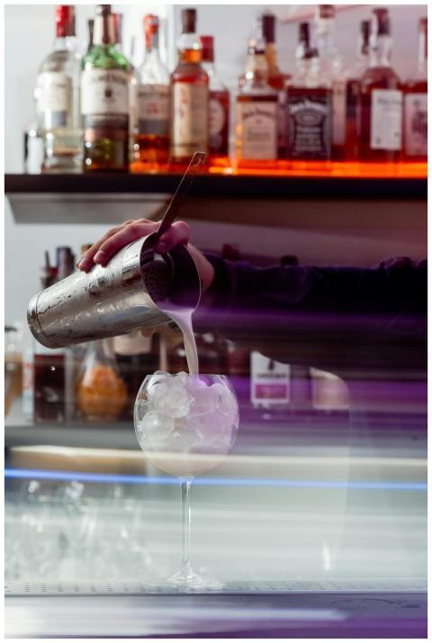 Bartender pours a cocktail into a glass with ice i
