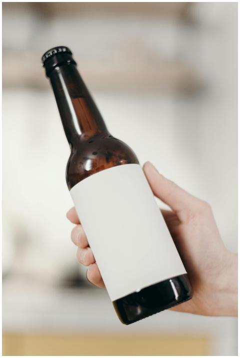 Close-up of a hand holding a blank labeled beer bo