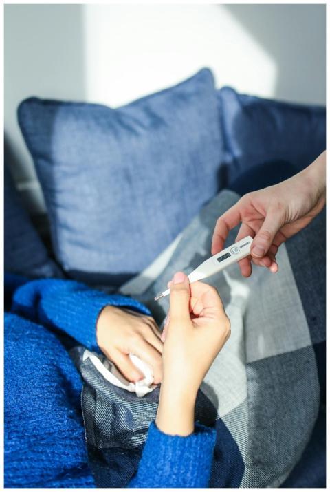 A woman checks her temperature using a digital the