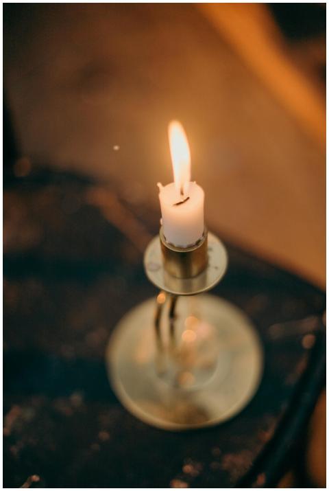 A warmly lit candle in a brass holder creates a co