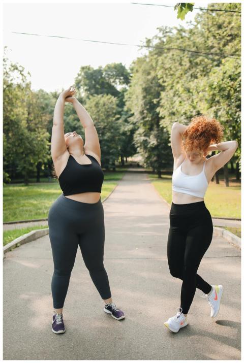 Two women stretching in a park, embracing wellness