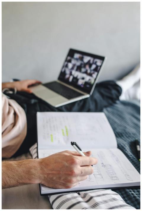 Student taking notes with a notebook during an onl