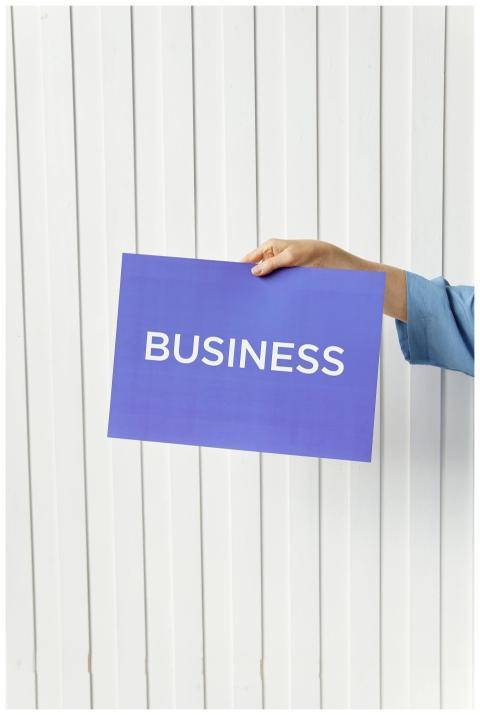 A hand holds a blue placard with 'Business' signag