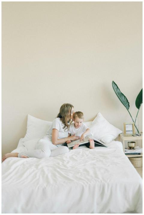 A mother and child reading a book together on a be