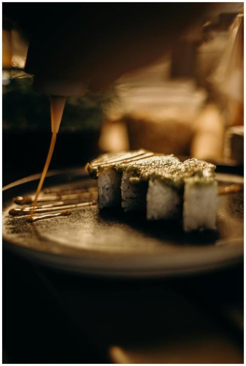 Close-up of a gourmet sushi roll being artfully dr
