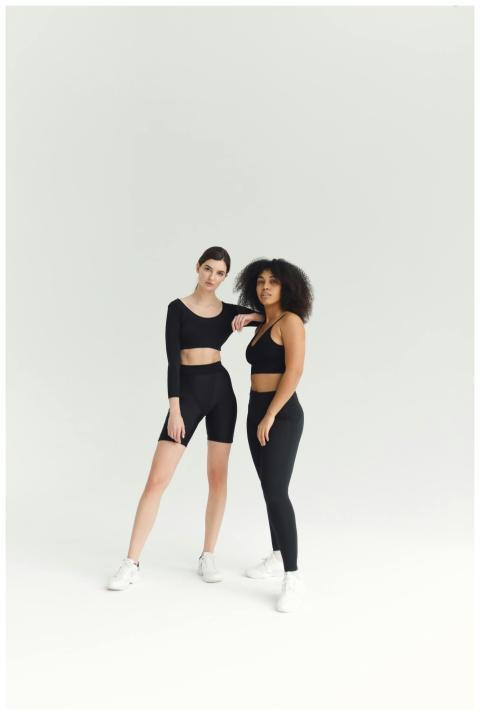 Two women in black activewear pose confidently in
