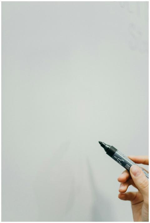 Close-up of hand holding black marker, ready to wr