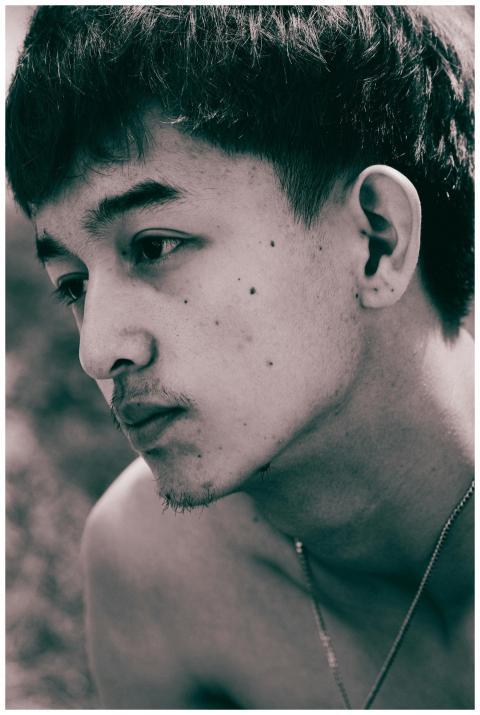 A close-up portrait of a pensive young man looking