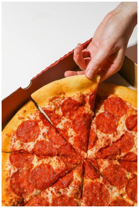 Close-up of a hand picking a pepperoni pizza slice